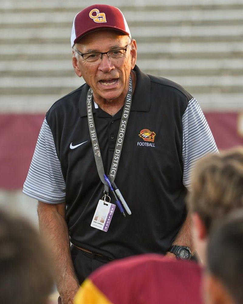 Coach Jerry Campbell speaking with his football team on the field
